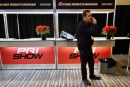 A Performance Racing Industry Trade Show attendee takes a phone call near an information booth decorated with poinsettias at the Indiana Convention Center. (DirtonDirt.com)